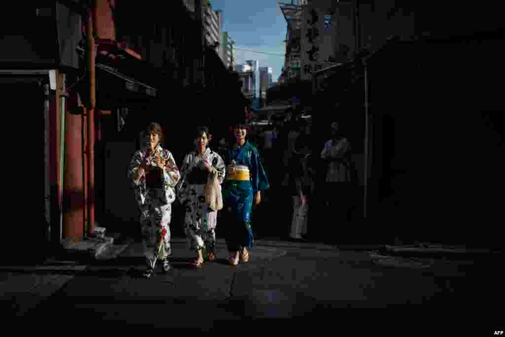Women wearing kimonos walk along a street in Tokyo&#39;s Asakusa district, Japan.
