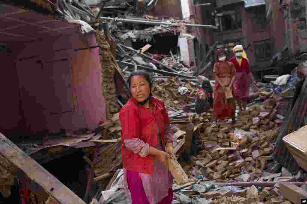 زن نپالی در جستجوی باقی مانده اموال خود، آوار را از خانه ویران شده اش برمیدارد.