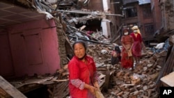 Nepalese women remove debris searching their belongings from their house that was destroyed a week ago during the earthquake in Bhaktapur, Nepal, Sunday, May 3, 2015.