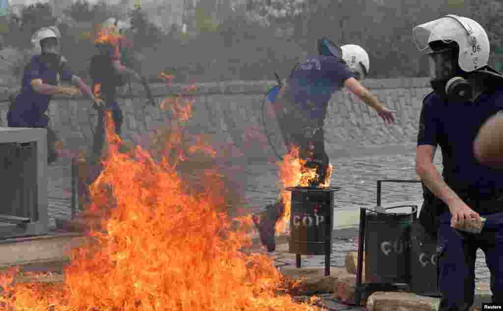 Riot police run away from the flames of a fire bomb thrown by protesters as they demonstrate to blame the ruling AK Party (AKP) government on the mining disaster in western Turkey, in Ankara May 14, 2014. Rescuers pulled more dead and injured from a coal
