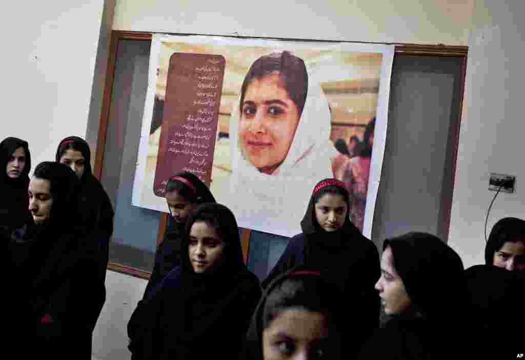 Anak-anak sekolah di Pakistan berkumpul di bawah poster teman sekelas mereka yang terluka, Malala Yousafzai, di sekolah khusus perempuan Khushal School for Girls, di Mingora, Swat Valley, Pakistan (15/11/2012). (AP/Anja Niedringhaus)