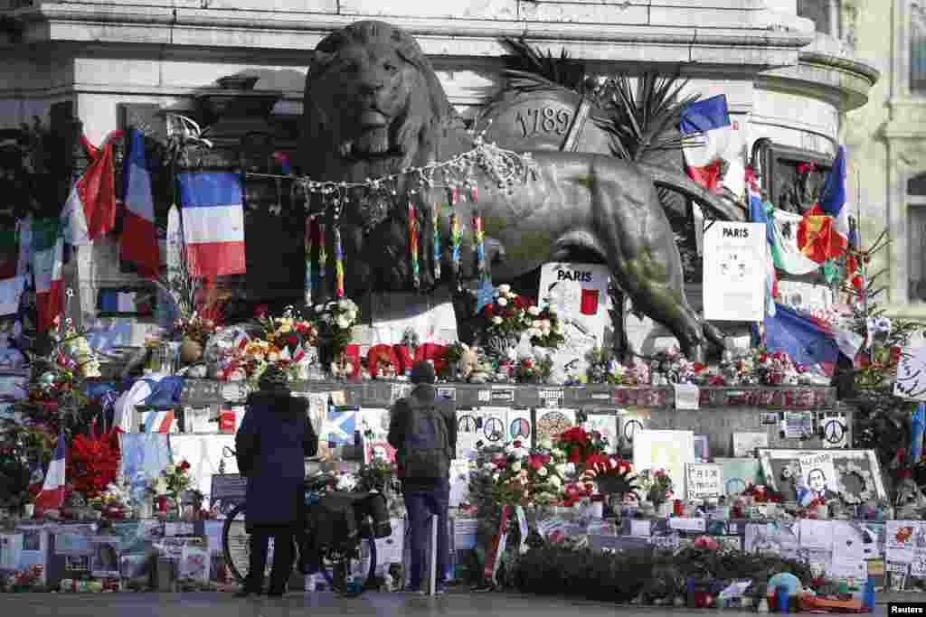 Orang-orang memandangi bunga-bunga dan barang-barang persembahan lain untuk mengenang korban serangan penembakan tahun lalu pada bulan Januari dan November dekat patung Place de la Republique di Paris, Perancis, 6 Januari 2016.
