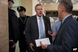 Rep. Mark Meadows, R-N.C., chairman of the conservative Freedom Caucus, left, joined by House Armed Services Committee Chairman Mac Thornberry, R-Texas, center, and Rep. Lamar Smith, R-Texas, arrives for a meeting of fellow Republicans on the first morning of a government shutdown, at the Capitol in Washington, Jan. 20, 2018.