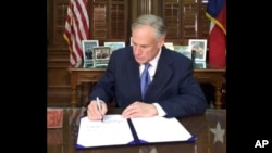 In this frame from video posted by the Office of the Governor, Republican Gov. Greg Abbott signs a so-called "sanctuary cities" ban in Austin Texas, May 7, 2017. 