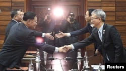 Kwon Hyok Bong, director of the Arts and Performance Bureau in North Korea's Culture Ministry, shakes hands with Lee Woo-sung, head of the South Korean delegation, after their meeting at Tongilgak, the North's building in the truce village of Panmunjom, North Korea, Jan. 15, 2018. 
