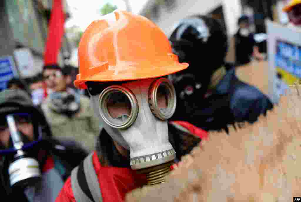 A Turkish protestor wearing a gas mask and a hard hat takes cover during clashes with riot police who prevent demonstrators from reaching Taksim Square in Istanbul for a May Day rally.