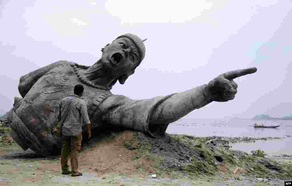 A bystander looks at a part of a bronze statue of Lachit Borphukan, which is set to be installed in the middle of the River Brahmaputra in Guwahati, India. Lachit Borphukan was a commander in the Ahom kingdom known for his leadership in the 1671 Battle of Saraighat that thwarted the last major attempt by Mughal forces to extend their empire into Assam.