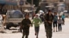 FILE - Syrian Democratic Forces female fighters run with children in the town of Tabqa, Syria, after SDF captured it from Islamic State militants in May 2017.