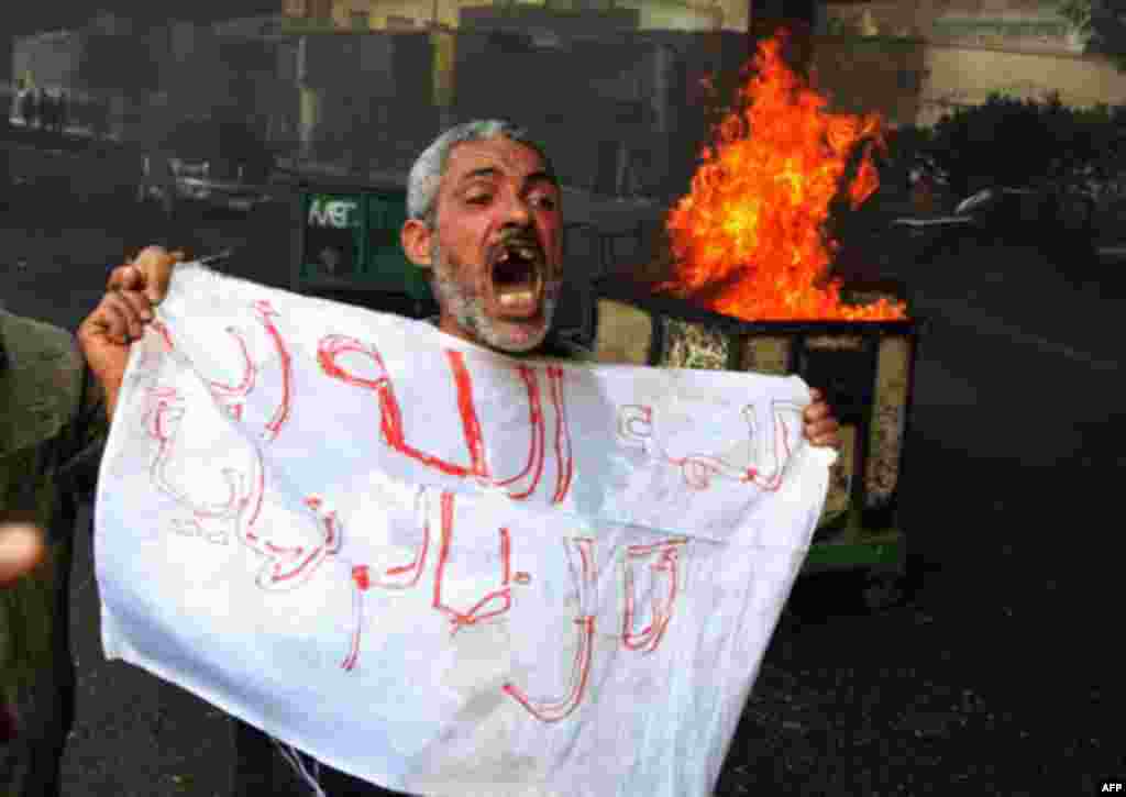 A protester shouts in front of a burning barricade during a demonstration in Cairo January 28, 2011. Police and demonstrators fought running battles on the streets of Cairo on Friday in a fourth day of unprecedented protests by tens of thousands of Egypti