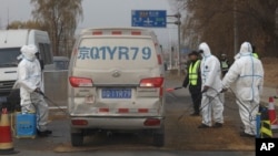 FILE - Workers disinfect passing vehicles in an area after the latest incident of African swine flu outbreak on the outskirts of Beijing, China, Nov. 23, 2018.