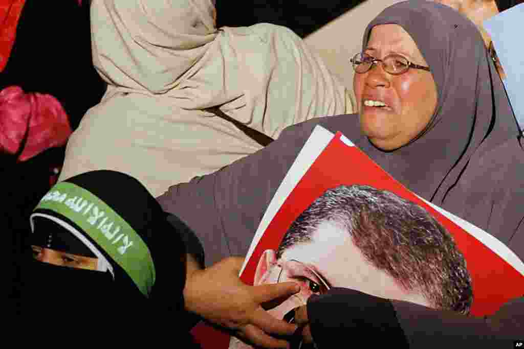 Seorang pendukung Mohammed Morsi menangis sambil memeluk fotonya menyusul pengumuman kudeta dari Menteri Pertahanan di televisi pemerintah di Kairo (3/7).