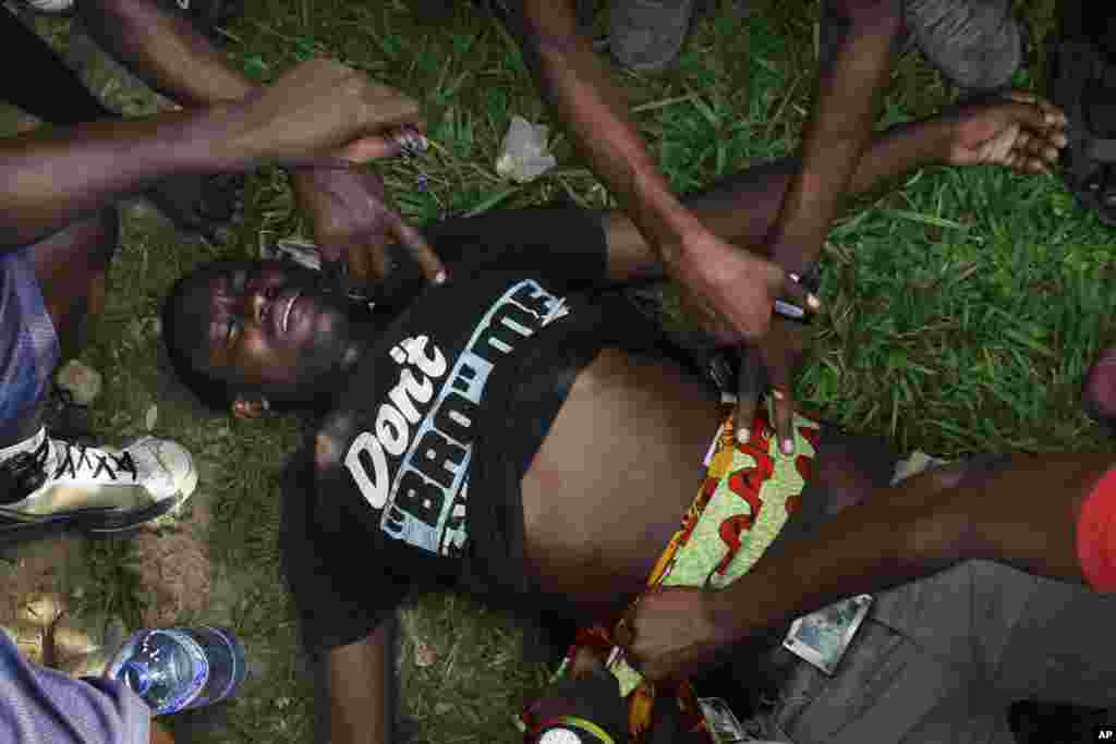 A man suffering from a bullet wound to the stomach waits for an ambulance in the Musaga neighborhood of Bujumbura, May 21, 2015.