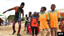 Un artiste danse avec des jumeaux lors de la célébration de la journée des jumeaux à Abobo, dans la banlieue d'Abidjan, le 8 septembre 2018.