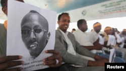 A Somali journalist holds a poster bearing the image of Abdiaziz Abdinur in Mogadishu in this January 27, 2013, file photo..
