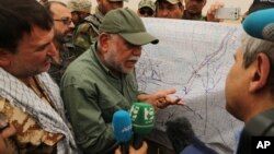 FILE - Iraqi militia leader Hadi al-Amiri of the Badr Brigades Shiite militia explains a battle plan to his fighters near the front line on the outskirts of Fallujah, Anbar province, Iraq, June 1, 2015. 