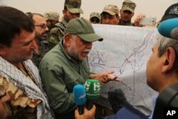 FILE - Iraqi militia leader Hadi al-Amiri of the Badr Brigades Shi'ite militia explains a battle plan to his fighters near the front line on the outskirts of Fallujah, Anbar province, Iraq, June 1, 2015.
