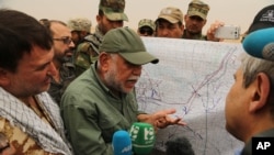 FILE - Iraqi militia leader Hadi al-Amiri of the Badr Brigades Shiite militia explains a battle plan to his fighters near the front line on the outskirts of Fallujah, Anbar province, Iraq, June 1, 2015. 