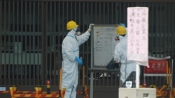 Guards read a whiteboard near the Fukushima-1 nuclear plant's main gate
