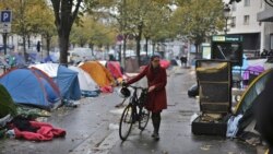 Seorang perempuan berjalan membawa sepedanya melewati tenda-tenda yang dibangun oleh para migran di Paris, Prancis, pada 4 November 2016. (Foto: AP/Thibault Camus)