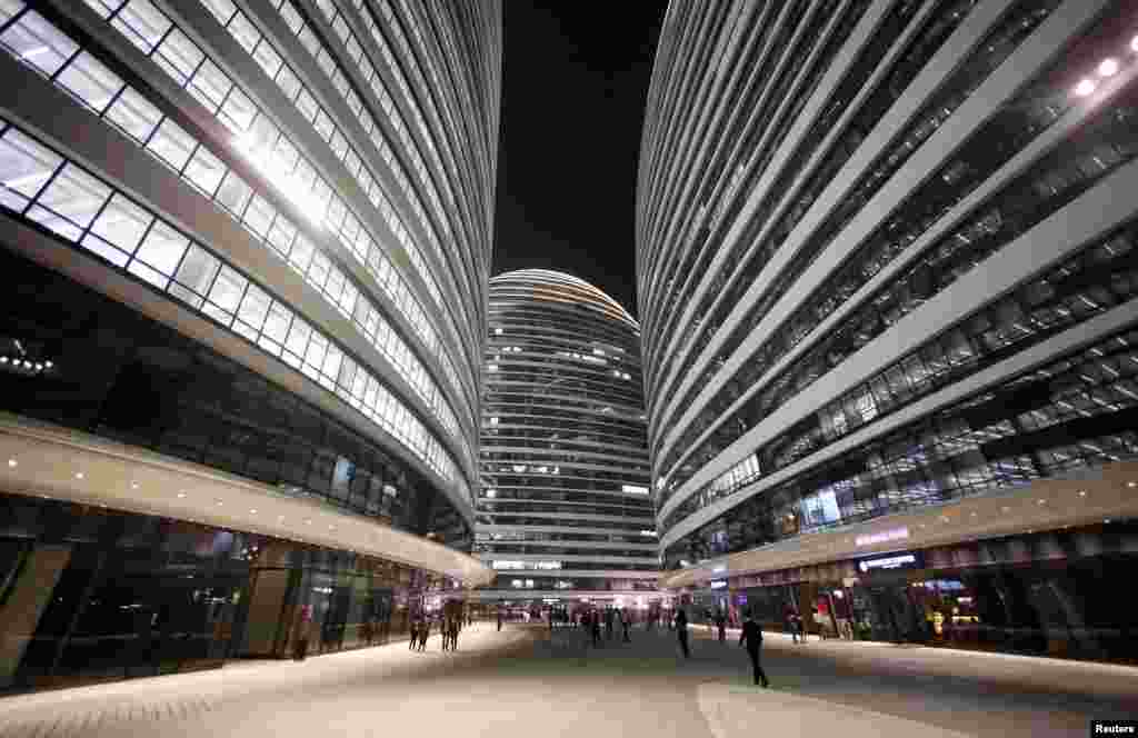 FILE - People walk between the buildings of Wangjing SOHO on the opening day of the compound, in Beijing, China, Sept. 20, 2014. Wangjing SOHO was designed by Pritzker Prize winner Iraqi-British architect Zaha Hadid.
