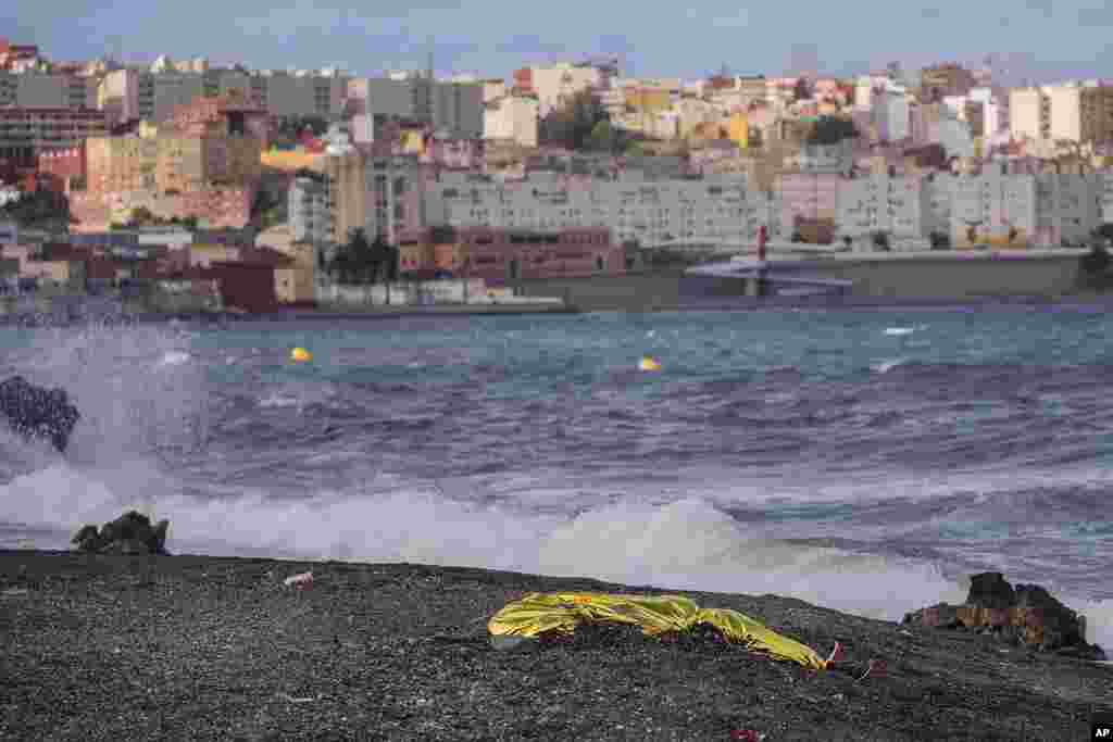 The body of a young man is seen covered with an emergency blanket after being recovered by Spanish police from waters near the border between Morocco and Spain&#39;s north African enclave of Ceuta.