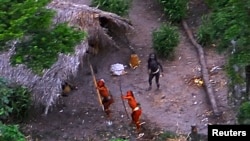 FILE - Members of an uncontacted Amazon Basin tribe and their dwellings are seen during a flight over the Brazilian state of Acre along the border with Peru in this May 2008 photo distributed by Funai, the government agency for the protection of indigenous people.