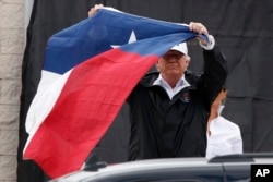 FILE - President Donald Trump holds up a Texas flag after speaking with supporters outside Firehouse 5 in Corpus Christi, Texas, Aug. 29, 2017, where he received a briefing on Harvey relief efforts.