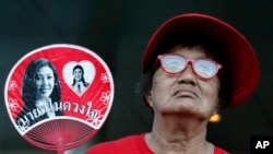 A supporter of Thai former Prime Minister Yingluck Shinawatra holds a fan outside the Supreme Court in Bangkok, Thailand, Wednesday, Sept. 27, 2017. (AP Photo/Sakchai Lalit)