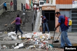 Workers clean the street after a protest in Caracas, Venezuela, Jan. 24, 2019.