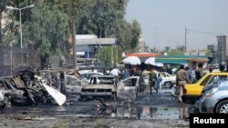 Petugas keamanan Irak memeriksa kendaraan yang hancur akibat serangan bom di Khazimiyah, Baghdad (15/8).