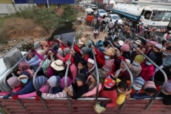 Cambodian garment factory workers ride on the back of a truck as they head to their homes at the evening traffic jump of Sre Cheah village outside Phnom Penh, Cambodia, Saturday, Jan. 11, 2020. (AP Photo/Heng Sinith)