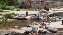 People cool off in the water at the confluence of the South Platte River and Cherry Creek in Denver, Wednesday June 16, 2021. A heat wave continues to hover over the western U.S., pushing the temperature to 99 degrees in Denver. (AP Photo/Brittany Peterso