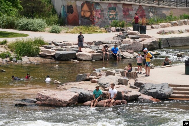 As pessoas se refrescaram na confluência do rio South Platte e Cherry Creek em Denver, quarta-feira, 16 de junho de 2021. Uma onda de calor continua pairando sobre o oeste dos EUA, elevando a temperatura para 99 graus em Denver.  (AP Photo / Brittany Peterso