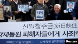 FILE - Lee Choon-shik, a victim of wartime forced labor during the Japanese colonial period, arrives with supporters holding portraits of fellow deceased laborers in Seoul, Oct. 30, 2018. 