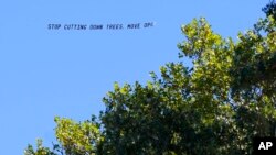 A plane tows a sign criticizing the cutting down of trees for the building of the Obama Presidential Center in Jackson Park during the groundbreaking ceremony for the center, in Chicago, Sept. 28, 2021.