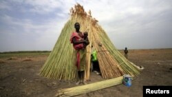 A woman from the Dinka tribe stands in front of her shelter near Bor, Jonglei state, in South Sudan, March 31, 2012.
