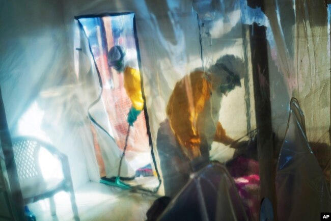 FILE - In this July 13, 2019 file photo, health workers wearing protective suits tend to an Ebola victim kept in an isolation tent in Beni, Democratic Republic of Congo.