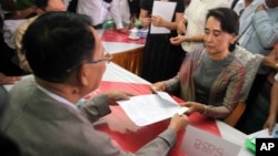 Myanmar opposition leader Aung San Suu Kyi, right, submits her documents for the upcoming general election at an election commission office on the outskirts of Yangon, Myanmar, July 29, 2015.