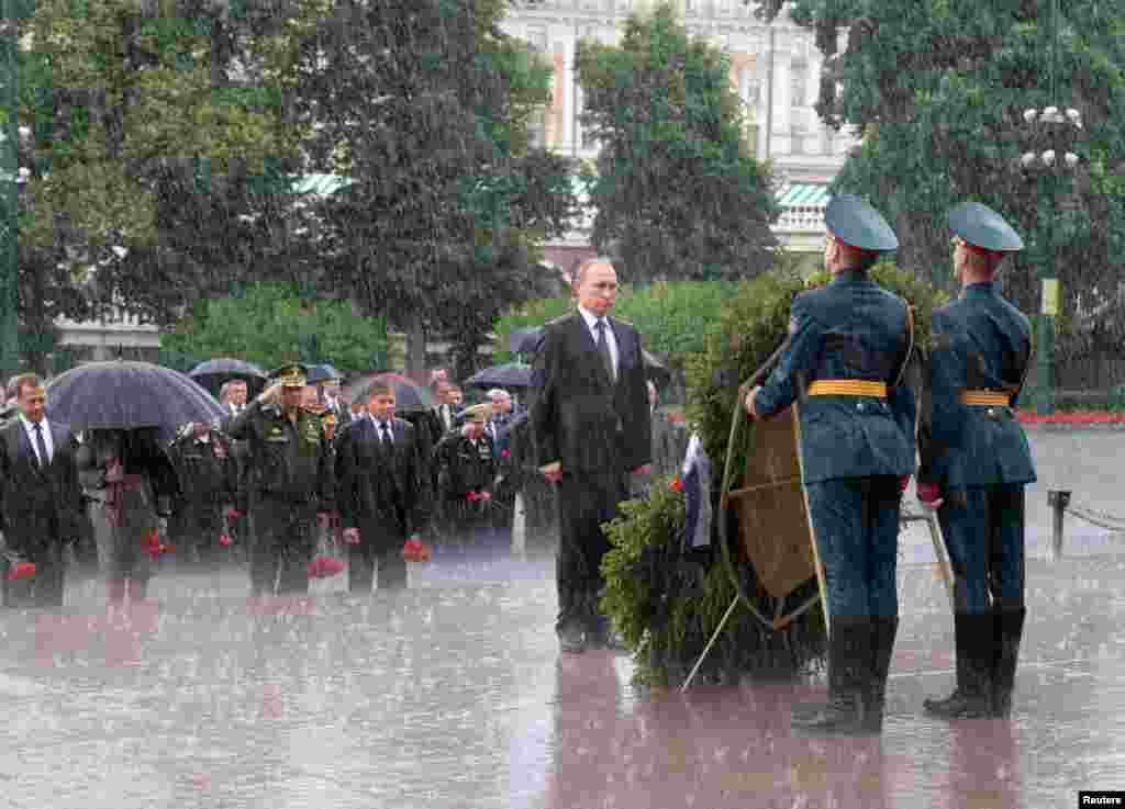 Dalam kondisi hujan deras, Presiden Rusia Vladimir Putin menerima pasukan kehormatan yang akan meletakkan karangan bunga dalam upacara menghormati tentara Rusia yang gugur dalam pertempuran melawan Nazi Jerman tahun 1941 di Moskow.