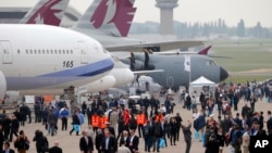 Visitors walk by a Boeing 777-300ER at left, and and Airbus A400M, at right, during the Paris Air Show, at Le Bourget airport, east of Paris, June 15, 2015.