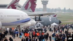 Visitors walk by a Boeing 777-300ER of China Airlines at left, and and Airbus A400M, at right, during the Paris Air Show, at Le Bourget airport, east of Paris, June 15, 2015.