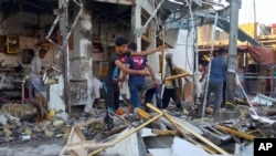 Para pemilik toko membersihkan puing-puing pasca ledakan bom di distrik al-Zubair, 550 kilometer sebelah tenggara Baghdad, Irak (6/10).