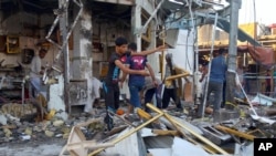 Shop owners clean up debris in the aftermath of a deadly car bomb explosion in a busy commercial district of al-Zubair, a suburb of the predominantly Shiite city of Basra, 340 miles (550 kilometers) southeast of Baghdad, Iraq, Tuesday, Oct. 6, 2015.