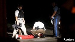 미국 미주리주 퍼거슨 시에서 흑인 사망 사건 1주년 행사가 열린 9일 총격전이 발생한 가운데, 경찰이 쏜 총에 맞은 남성이 바닥에 쓰러져 있다.