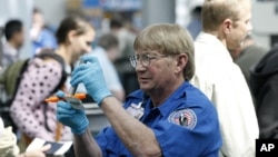 A TSA agent looks over a license at a security check point.