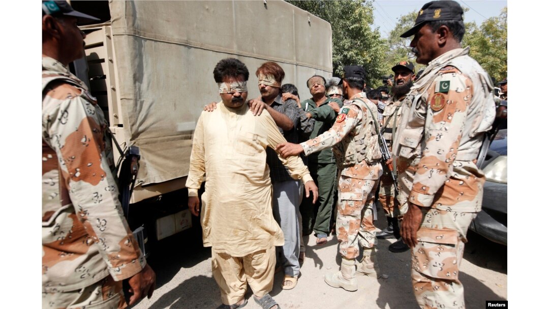 FILE - Paramilitary soldiers escort blindfolded men, detained during a raid, to be delivered to an anti-terrorism court in Karachi, Pakistan, March 12, 2015.