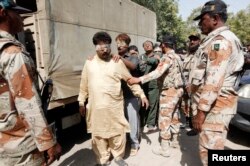 FILE - Paramilitary soldiers escort blindfolded men, detained during a raid, to be delivered to an anti-terrorism court in Karachi, Pakistan, March 12, 2015.