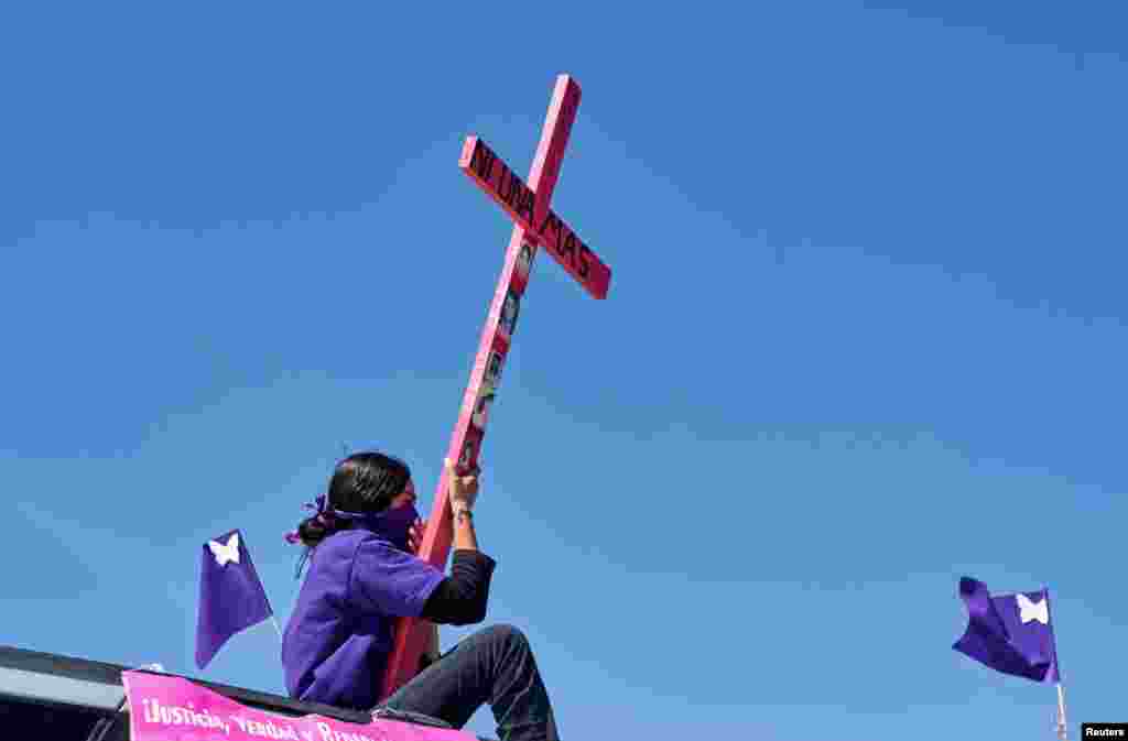 A mother seen atop a vehicle holding a cross with a sign reading &quot;Not one more&quot; during a caravan demanding an end to violence against women and femicide, ahead of a Women&#39;s Day protest, in Ciudad Juarez, Mexico, March 7 , 2021.