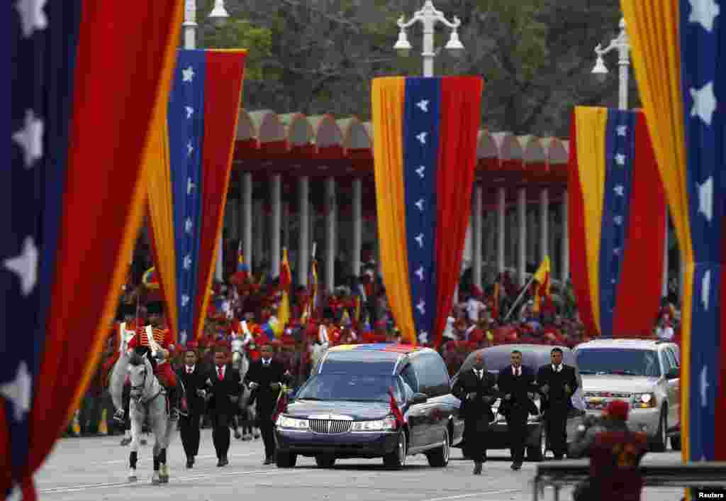 Guards run next to the hearse holding the body of Venezuela&#39;s late President Hugo Chavez during his funeral parade in Caracas. Hundreds of thousands of Venezuelans were on the streets for parade amid opposition protests that the government was exploiting president&#39;s death for election purposes.