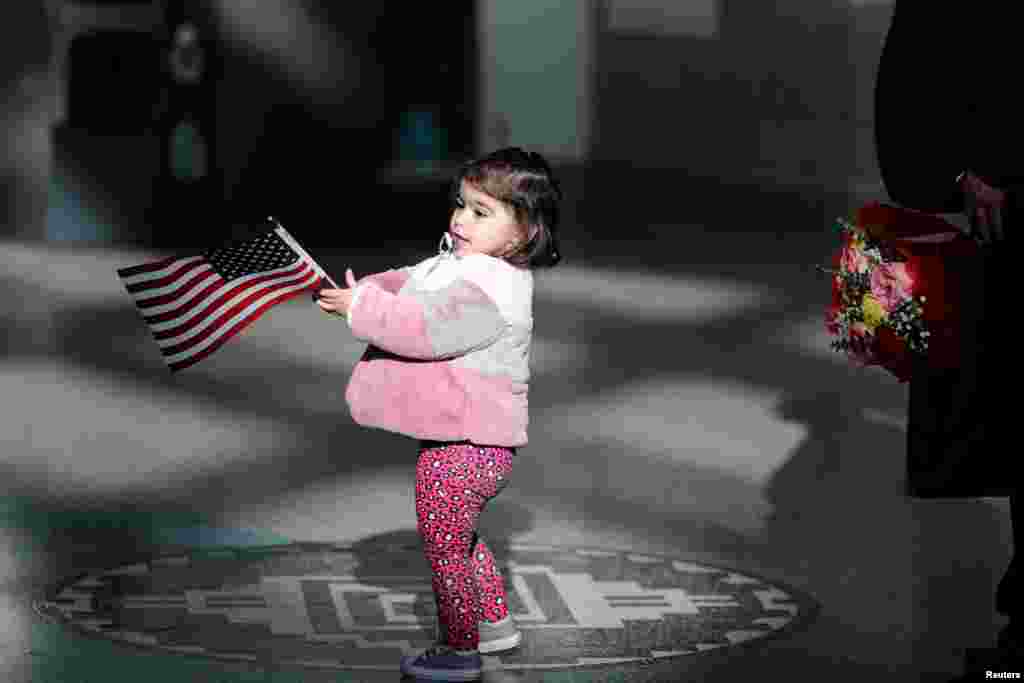 Ike Khajeek, 2, plays with an American flag as she waits for her mother, who is from Iraq, to be sworn in as a new United States citizen at a naturalization ceremony in Los Angeles, California, Dec. 19, 2018.